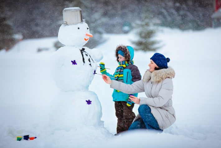 Женщина с ребенком лепит снеговика